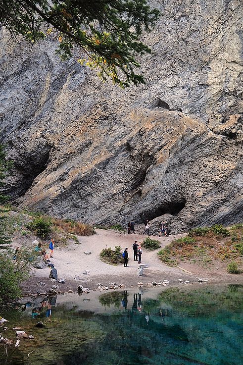 Randonneurs devant la falaise surplombant les eaux turquoise de Grassi Lakes.