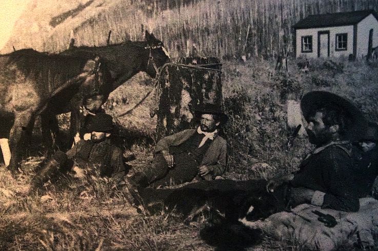 Photographie d'archives représentant des pionniers et un cheval devant une cabane, exposée au sommet de Sulphur Mountain à Banff.
