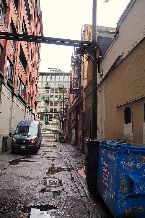 Van and waste containers in a graffiti-covered alley in the Gastown district in Vancouver.