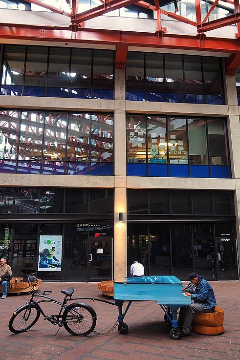 Blue piano towed by a bicycle in front of the 351 Abbott Street building in the Gastown district in Vancouver.