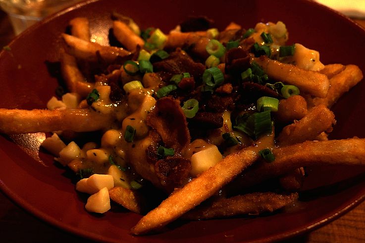 Poutine topped with cheese curds, bacon, and green onions in Vancouver.